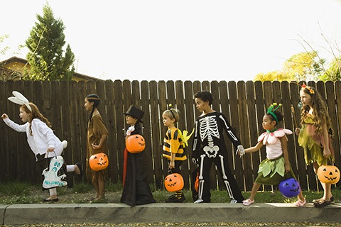 Kids waiting in a trick-or-treat line with costumes on.